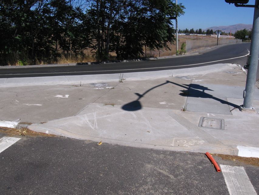 Crosswalk, ADA ramp to traffic lane at unsafe blind turn.